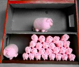 Ein Puppenhaus, oben ein einzelnes großes haekelschwein und unten ein weiteres großes haekelschwein mit sehr vielen kleinen haekelschweinen.