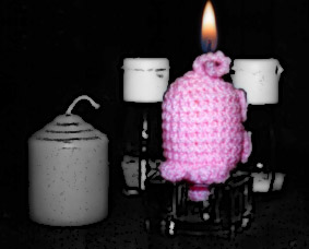 Ein haekelschwein kopfüber im Kerzenständer mit Flamme am Ringelschwanz.