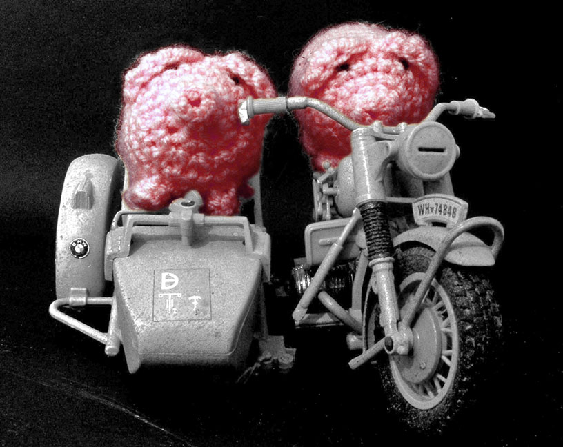Zwei haekelschweine auf einem kleinen Motorrad mit Beiwagen.