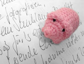 Ein haekelschwein auf einem handgeschriebenen Text.